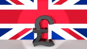 Currency symbol British Pound made of dark metal in spotlight in front of british flag