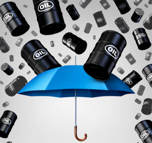 Falling oil protection concept as a group of crude petroleum barrels raining down with a blue umbrella as a security metaphor as a symbol for declining prices in fossil energy due to oversupply.